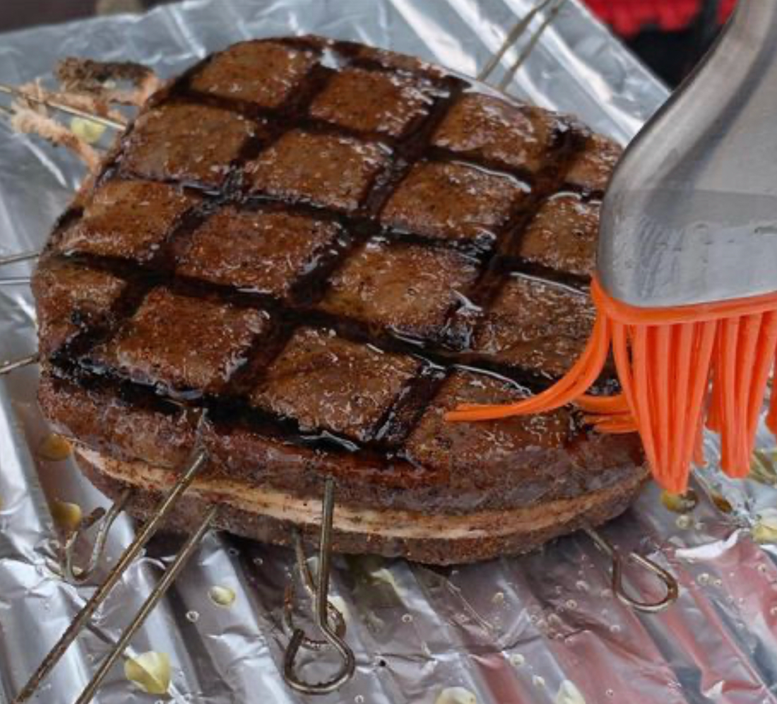 Perfectly grillmarked ribeye with silicone brush glazing tallow on a foiled rack